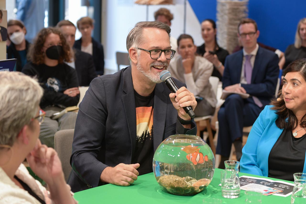 Michael Aechtler spricht mit Mikrofon im Publikum